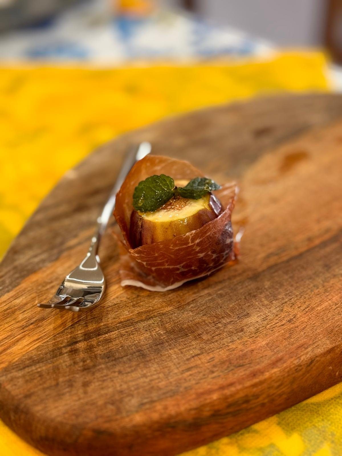 Fico avvolto nel capocollo con menta, sul tagliere