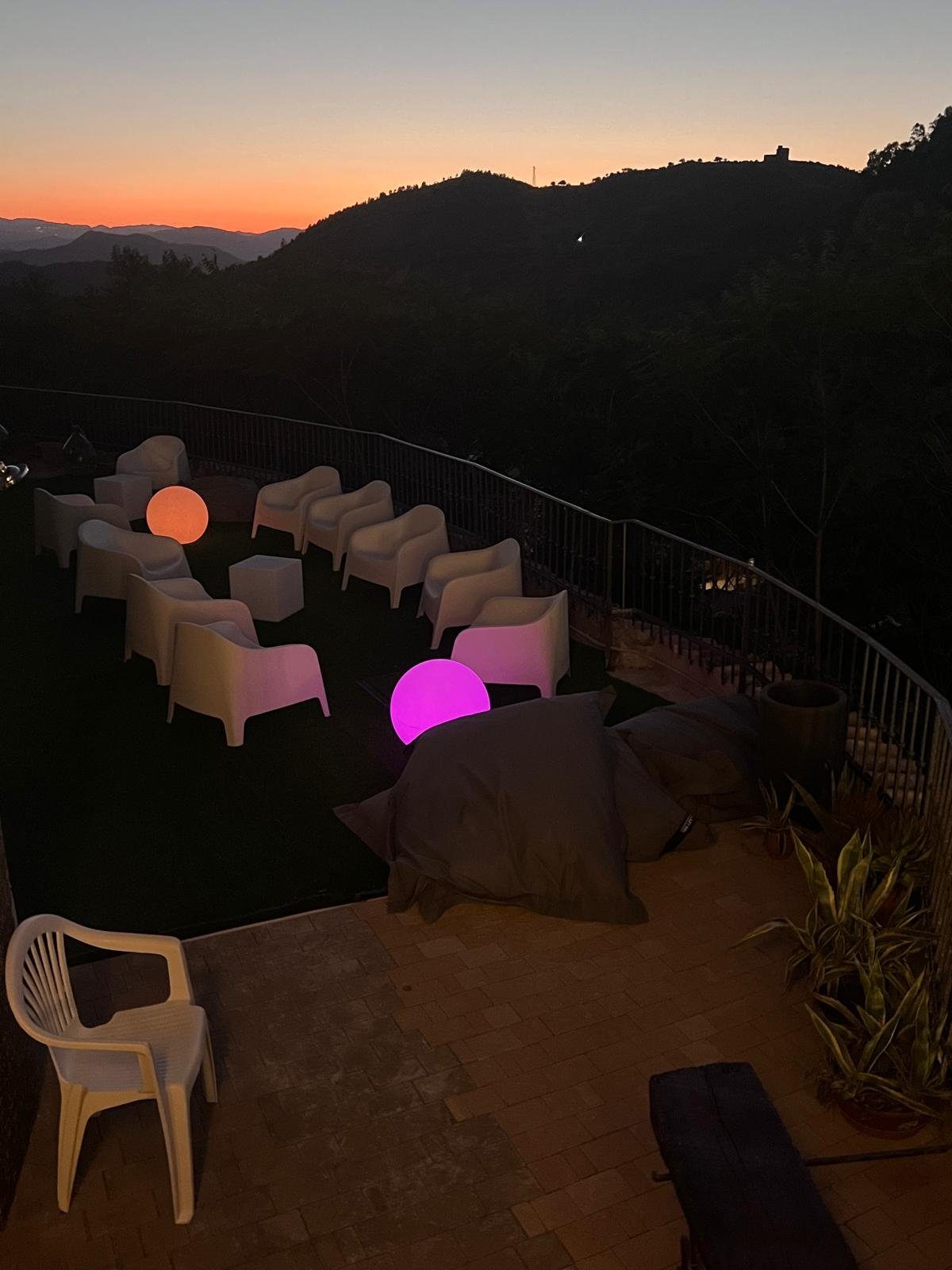 Il salotto all'aperto al tramonto, con le luci colorate e la vista sulle colline