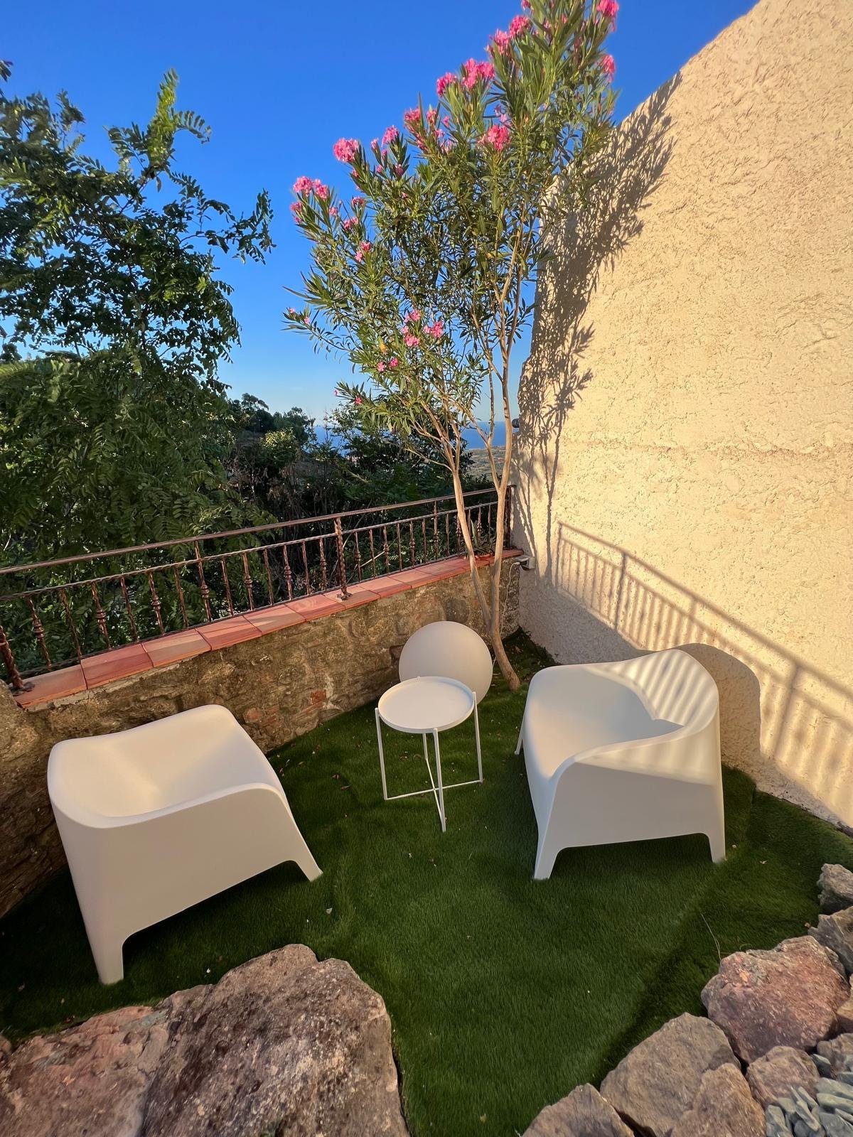 Poltroncine all'ombra dell'oleandro in fiore, con il panorama che si apre