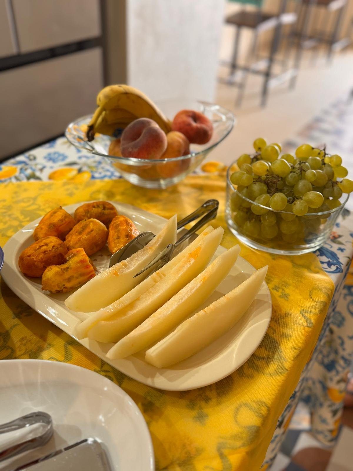 Colazione: frutta di stagione, melone bianco e frittelle dorate