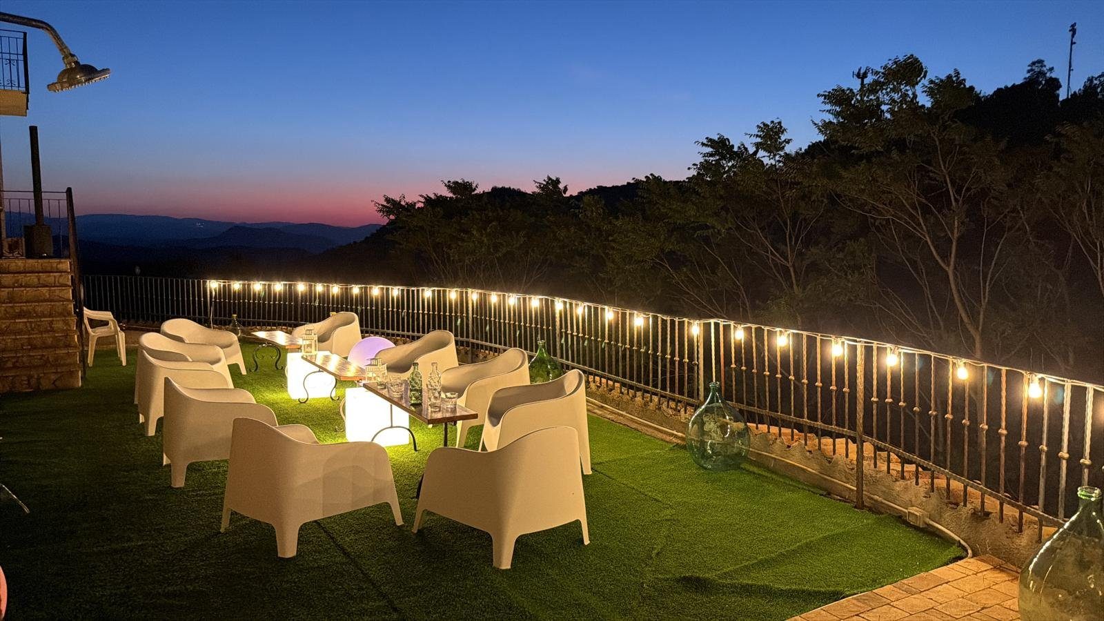 La terrazza all'imbrunire, con le lucine tra il verde e il cielo rosato